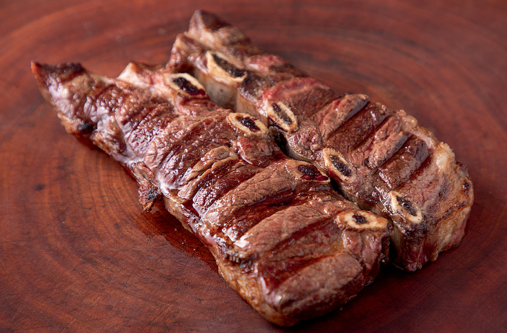 Dois pedaços de carne sobre uma tábua de madeira.