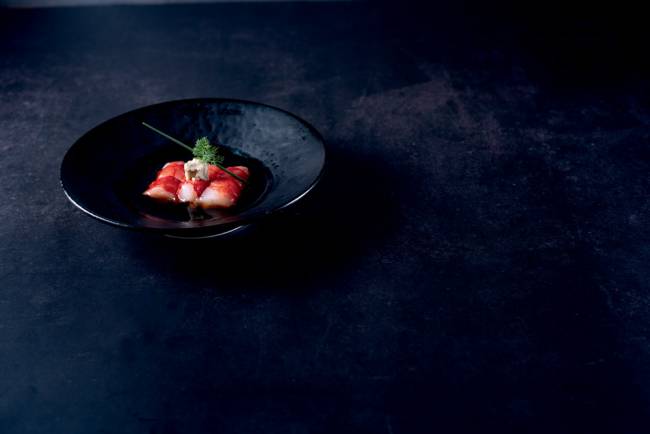 COMER & BEBER 2023 – Murakami Prato com três pedaços de peixe em fundo preto.