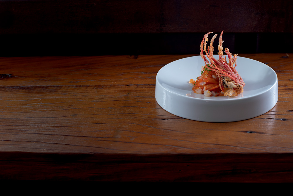 COMER & BEBER 2023 – Picchi Prato branco com peixes em cima de mesa de madeira.