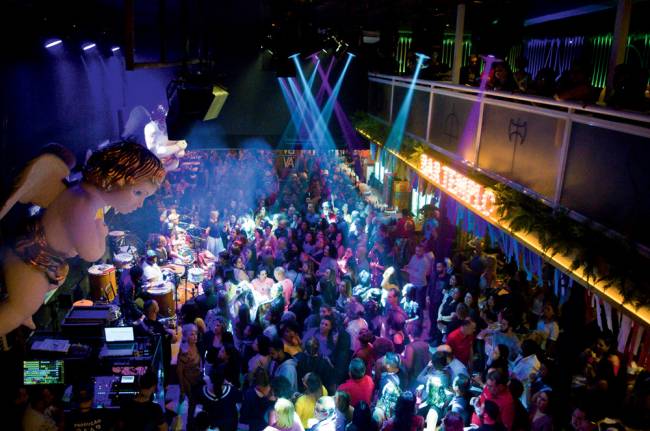 templo bar de fé Em primeiro plano, escultura de anjinho do alto. Abaixo, ambiente lotado em bar fechado