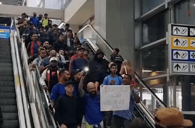 pessoas descendo uma escada rolante protestando