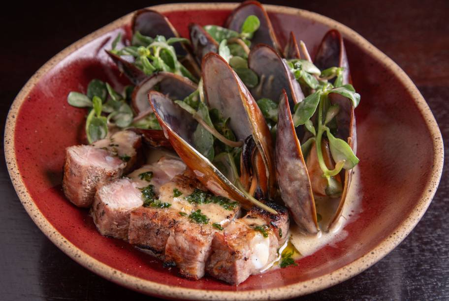 Mar e terra: mexilhões ao molho de manteiga com assado de tira de porco preto Mar e terra: mexilhões ao molho de manteiga com assado de tira de porco preto