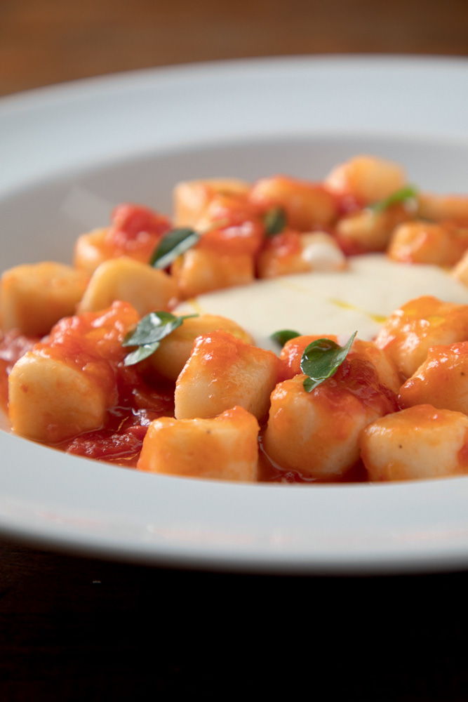 Nhoque ao molho vermelho em prato de lou&ccedil;a branca