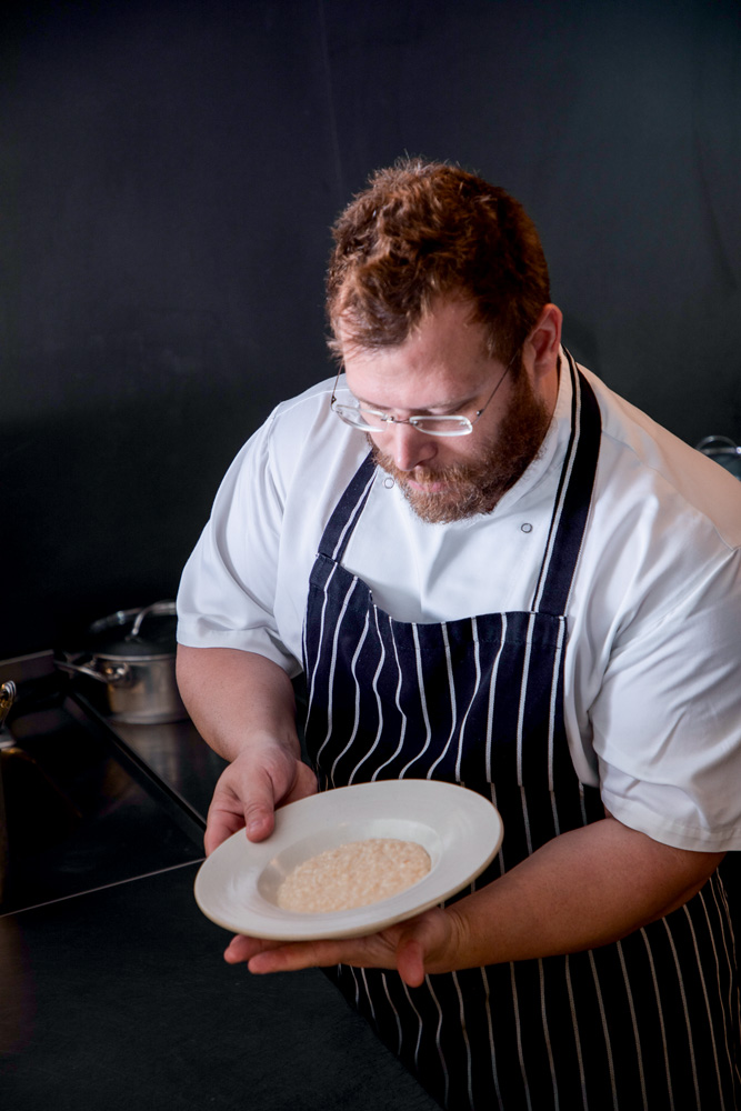 Simone Ristorante Chef de cozinha de avental segurando prato fundo com risoto