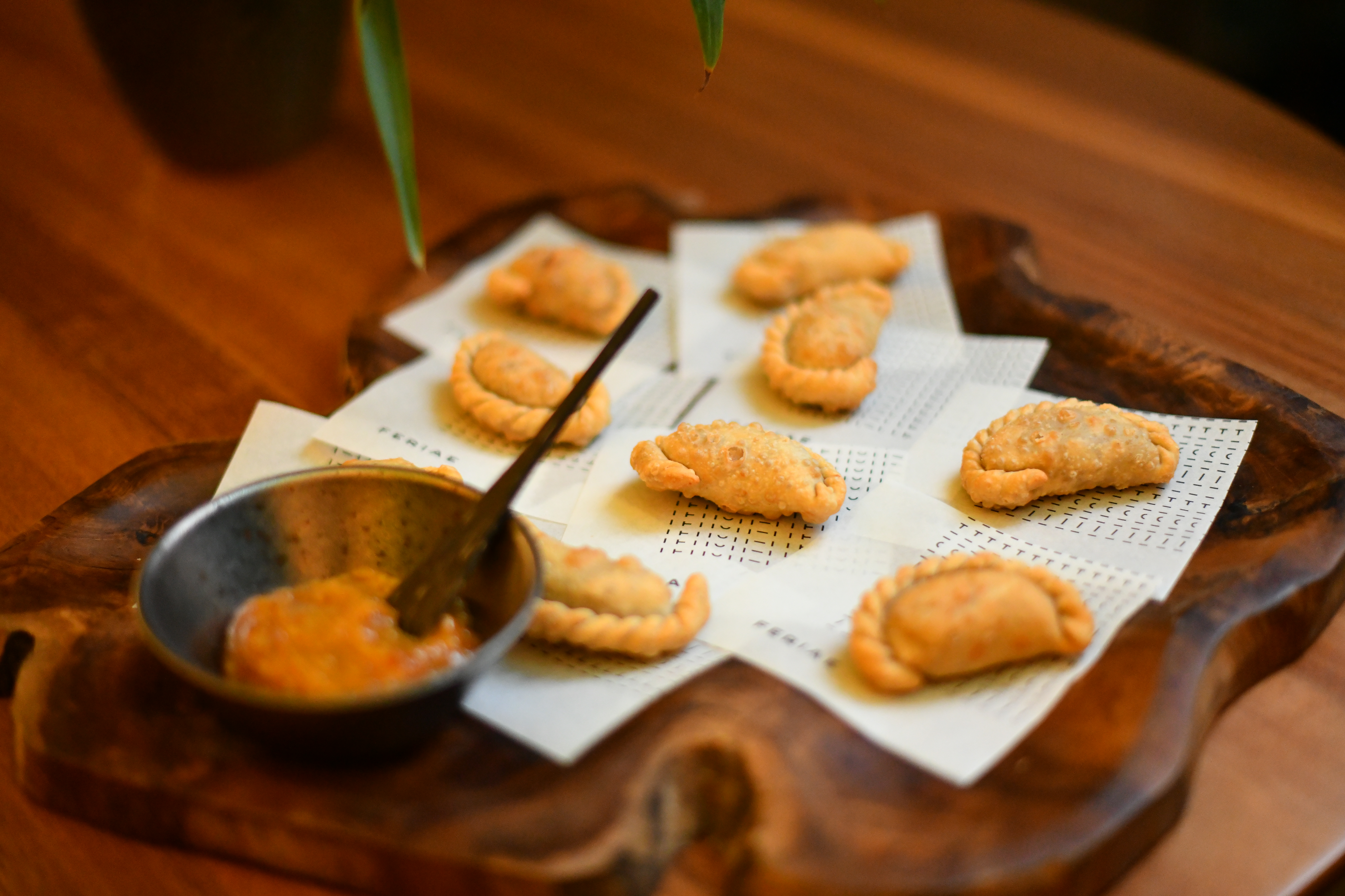 pasteizinhos em cima de bandeja de madeira com tigela de madeira de chutney
