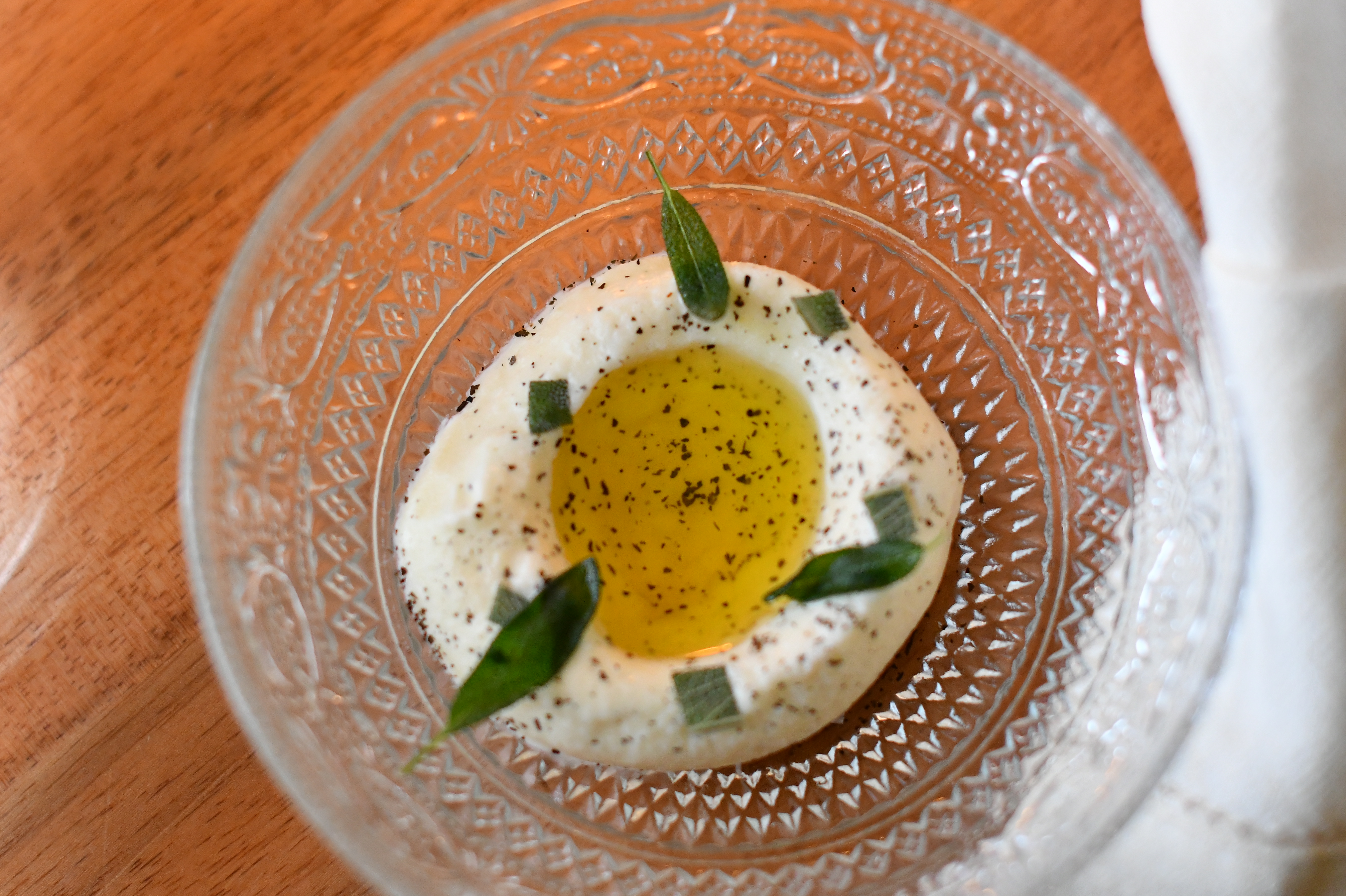 tigela de vidro com sorvete branco coberto por azeite e s&aacute;lvia