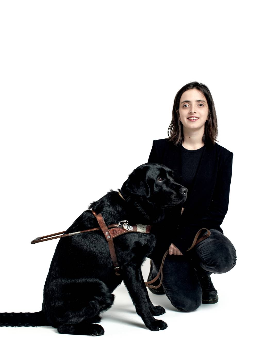 Maria Carvalhosa Imagem mostra Maria agachada ao lado de grande cachorro em fundo branco