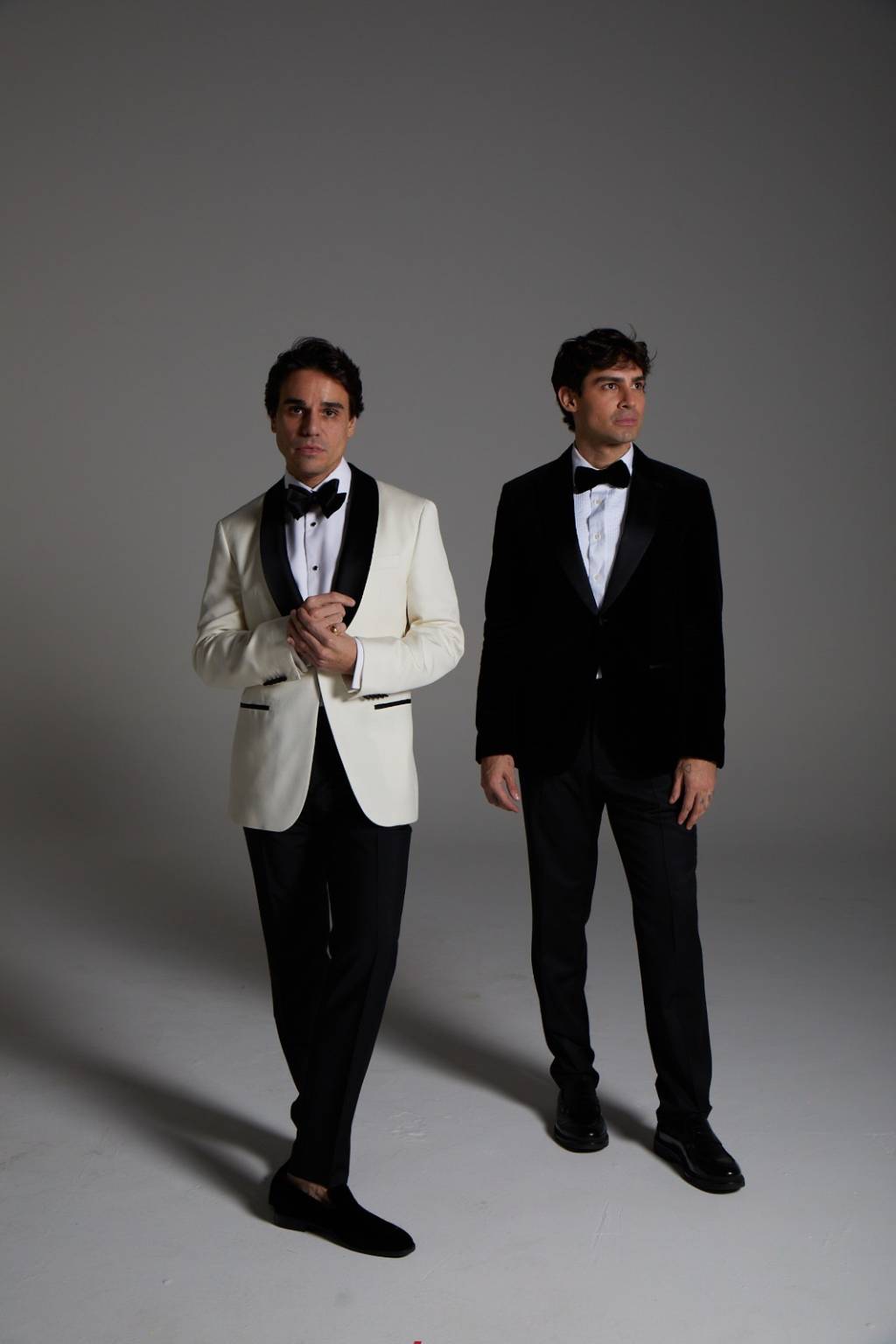 Beto Pacheco e Tiago Moura Crédito Gui Paganini e Thiago Bruno-Divulgação Dois homens brancos posam de smoking, o da esquerda com paletó branco