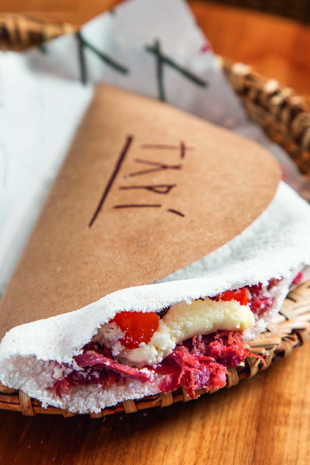 Tap&iacute;oca dentro de papel com logo da marca em cestinha de palha