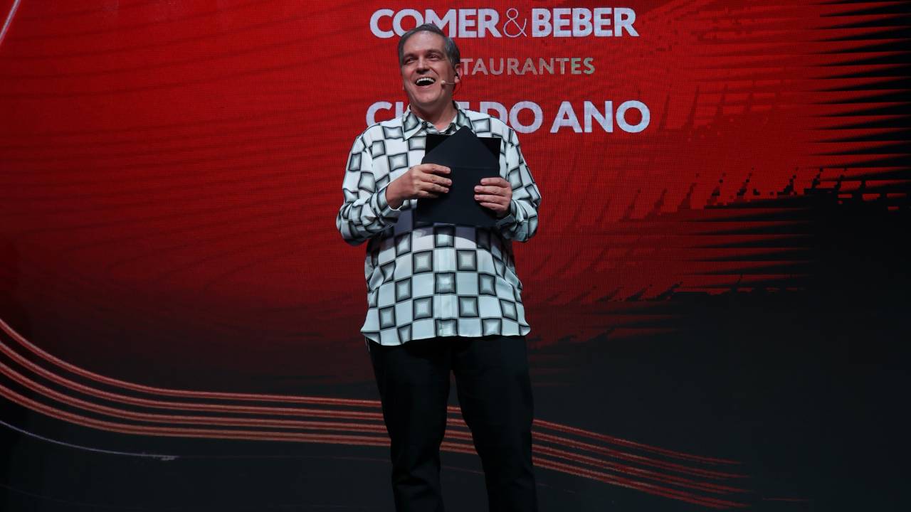 Homem microfonado em palco da premiação Comer & Beber.