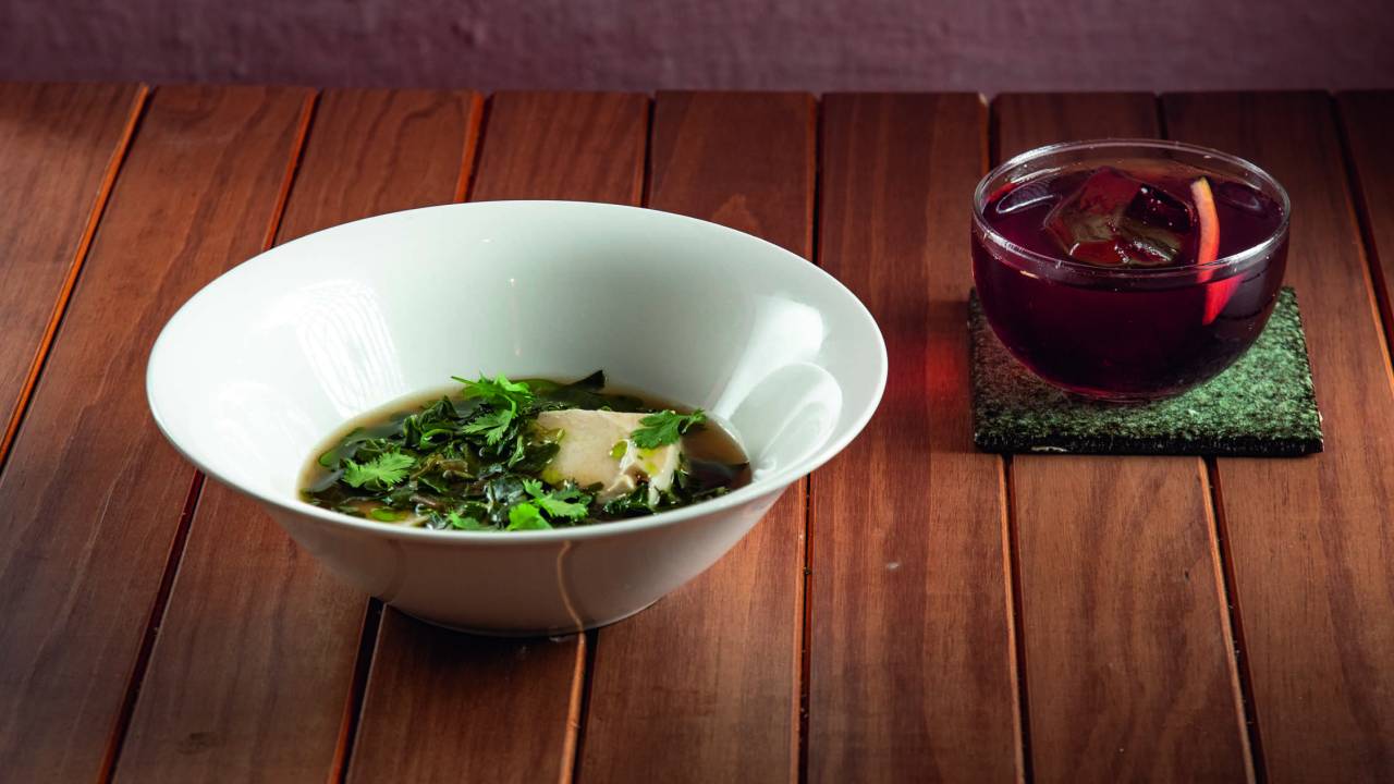 Prato redondo com tofu em caldo com brócolis e copo com umê fashioned