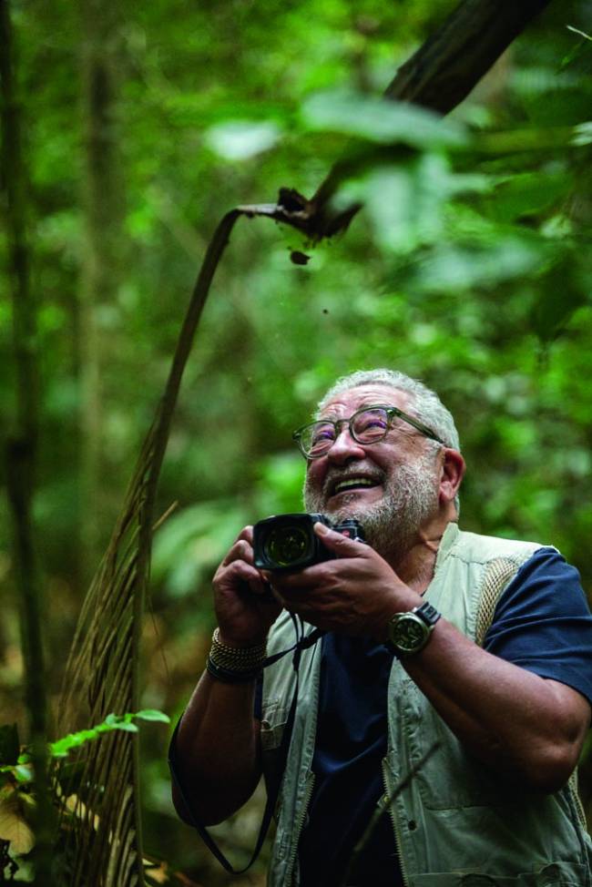 Fotógrafo com câmera na mão e sorrindo