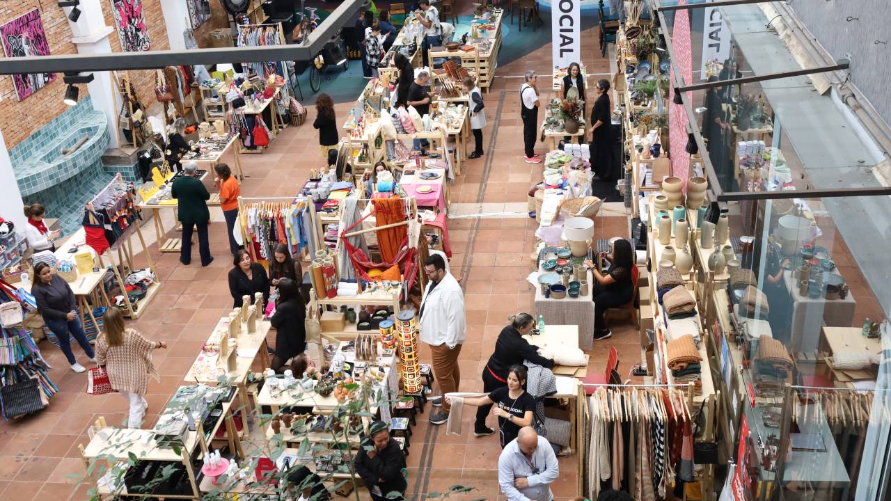 Foto do alto mostra vários estandes de bazar e pessoas nos corredores