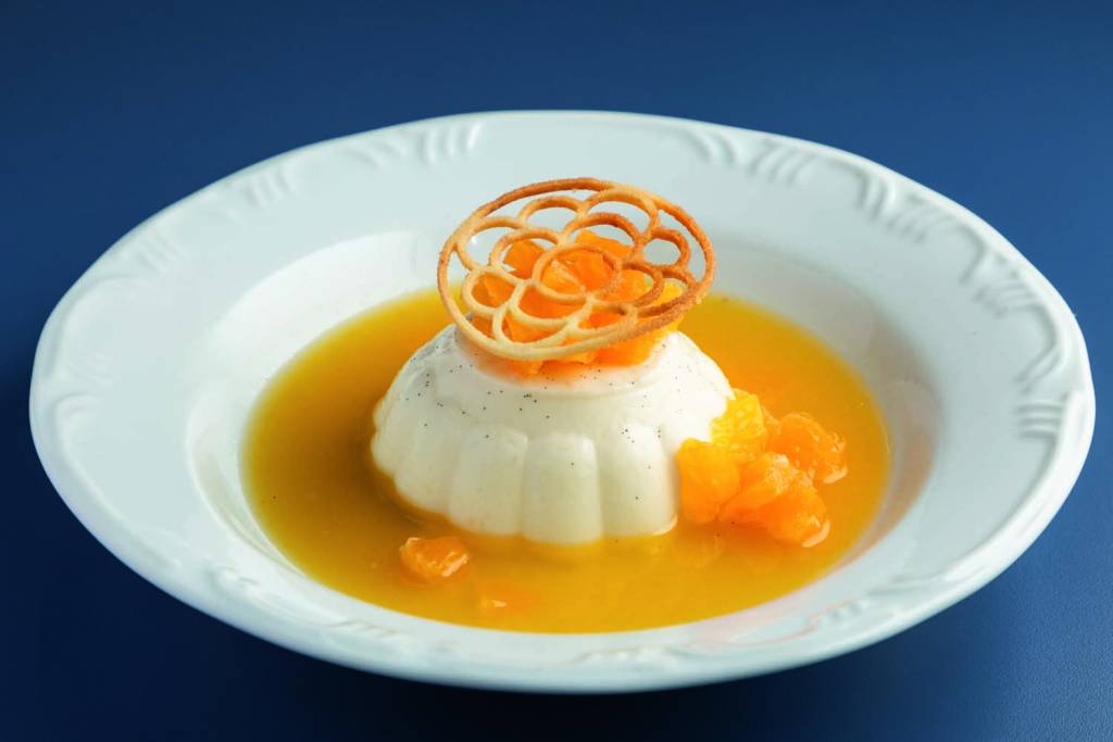 Pannacota com muita baunilha , calda de laranja e mel _ Mamma Vanzetto Prato redondo com panacota e fundo azul