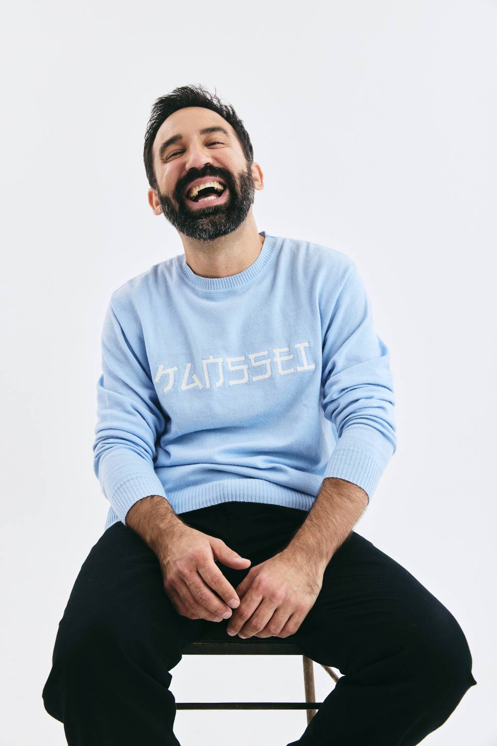 Vinicius Aguiar Crédito André Arthur-Divulgação.zip (8) Homem de barba preta veste moletom azul bebê, calça preta, e posa sentado rindo