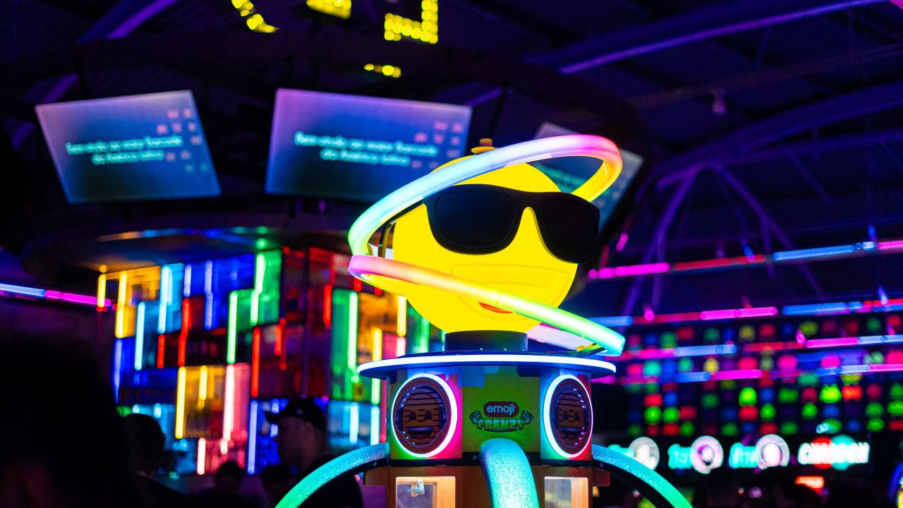 Imagem de casa de fliperama com bola amarela usando óculos de sol e vários neons