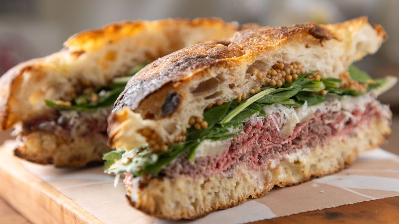 Pão cortado com recheio de rosbife e rúcula