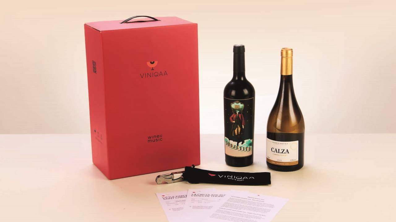 Garrafas e embalagem vermelha com abridor de garrafa em fundo rosado