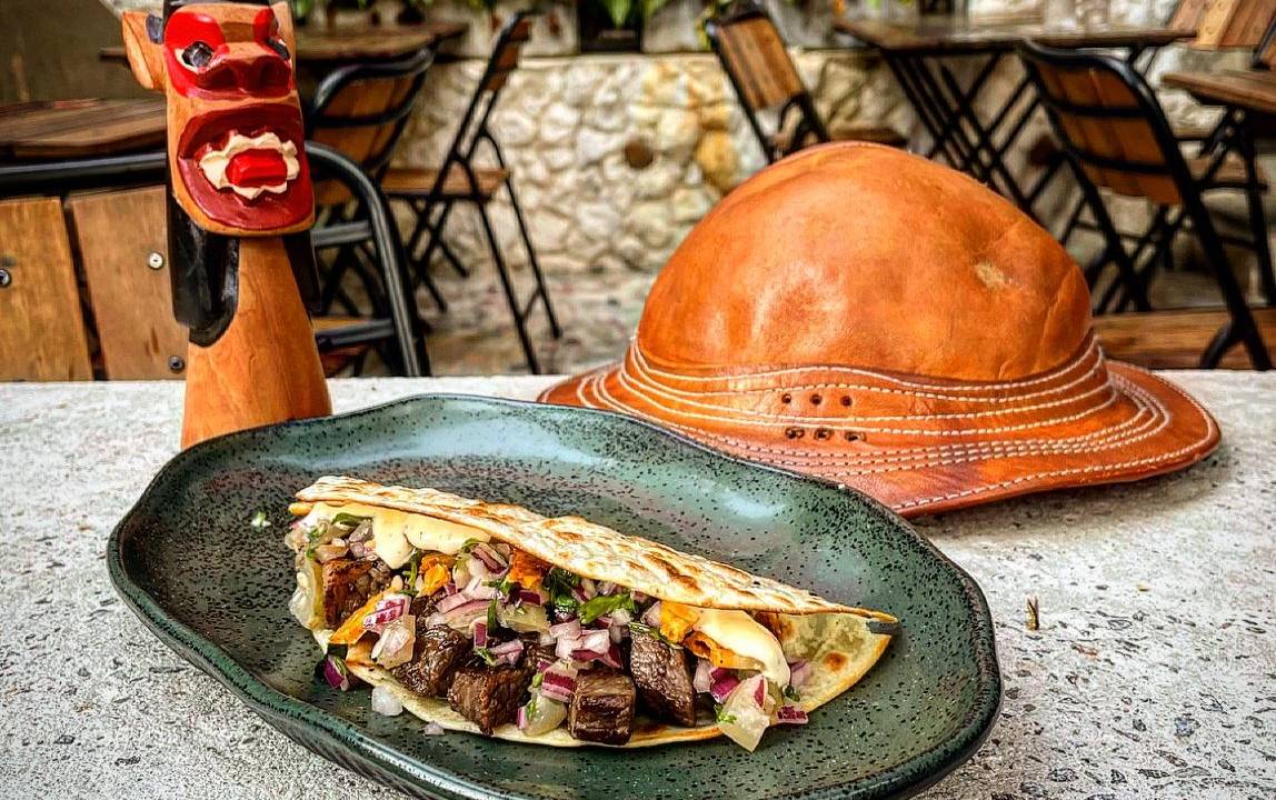 Taco com recheio em prato azul e loja ao fundo