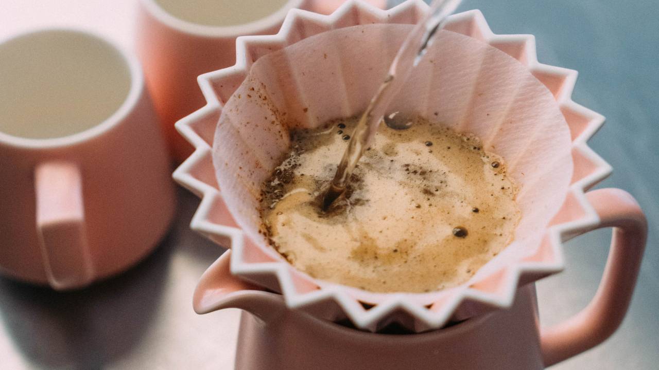 Café sendo coado e canecas ao fundo