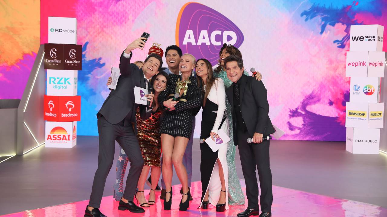 Grupo de pessoas se junta em palco rosa para tirar selfie