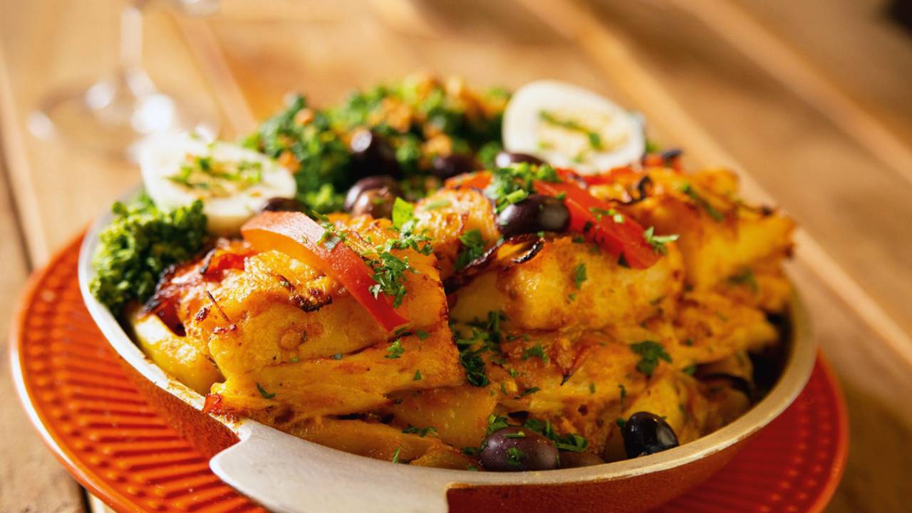 Bacalhau com tomate e azeitona em prato vermelho