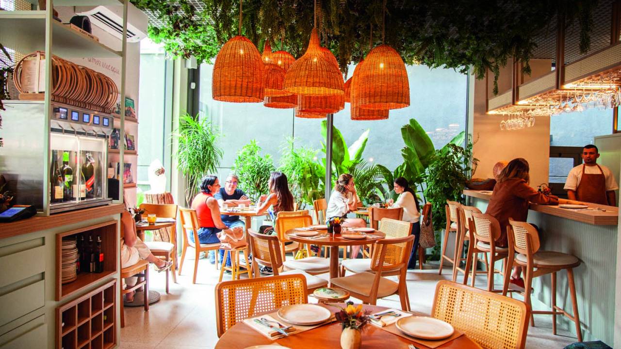 Ambiente com mesas de madeira e pessoas comendo
