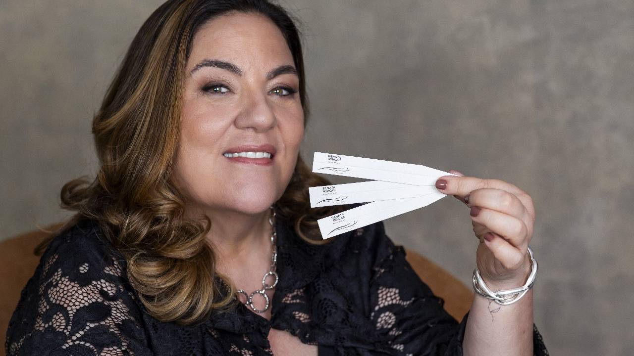 Renata Ashcar, mulher de cabelos lisos castanhos segurando papéis de perfume