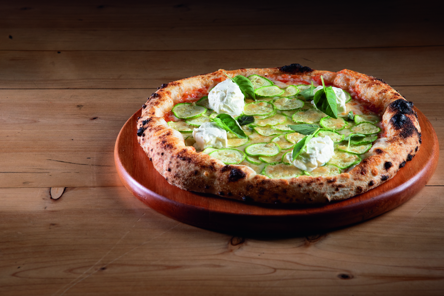 Disco de pizza em cima de prato e mesa de madeira