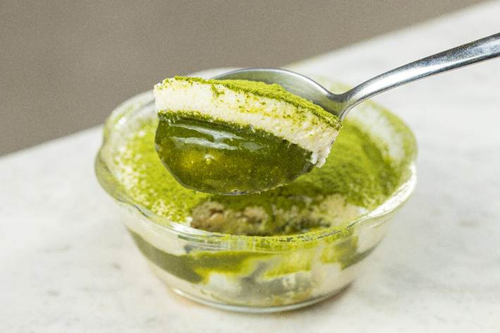 sobremesa de cor verde e colher tirando pedaço